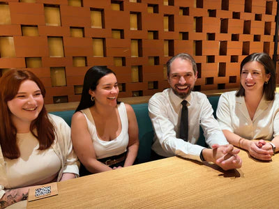 Group of four people sitting together in a room with a wooden paneled wall.