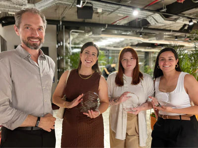 Group of four people holding awards in an indoor setting